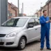 Kfz-Mechaniker übergibt einem Kunden vor einer Werkstatt die Autoschlüssel eines silbernen Hyundai.