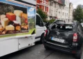 Geöffnete seitliche Verkaufsklappe eines Käse-Verkaufswagens ragt in die Fahrbahn, dahinter ein Dacia Duster mit zerbrochener Heckscheibe.