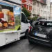 Geöffnete seitliche Verkaufsklappe eines Käse-Verkaufswagens ragt in die Fahrbahn, dahinter ein Dacia Duster mit zerbrochener Heckscheibe.