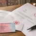 Führerschein liegt neben einem geöffneten Briefumschlag mit rotem Stempelaufdruck und einem amtlichen Schreiben auf einem Holztisch.