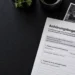 Anhörungsbogen wegen eines Blitzerverstoßes auf einem dunklen Schreibtisch mit Messfoto, Briefumschlag und Kugelschreiber.