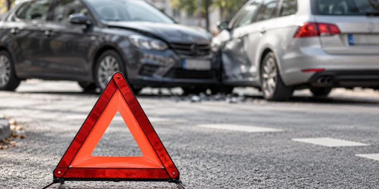 Warndreieck vor zwei beschädigten Fahrzeugen nach einem Verkehrsunfall zur Schuldfrage und Haftungsquote