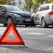 Warndreieck vor zwei beschädigten Fahrzeugen nach einem Verkehrsunfall zur Schuldfrage und Haftungsquote