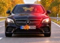 Schwarzer Mercedes fährt auf einer Herbstallee und wird geblitzt, ein Ahornblatt verdeckt einen Teil des Kennzeichens.