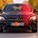 Schwarzer Mercedes fährt auf einer Herbstallee und wird geblitzt, ein Ahornblatt verdeckt einen Teil des Kennzeichens.