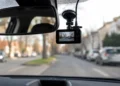 An der Windschutzscheibe montierte Dashcam im Auto mit Blick auf eine unscharfe Straße im Stadtverkehr