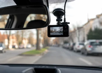 An der Windschutzscheibe montierte Dashcam im Auto mit Blick auf eine unscharfe Straße im Stadtverkehr