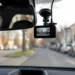 An der Windschutzscheibe montierte Dashcam im Auto mit Blick auf eine unscharfe Straße im Stadtverkehr
