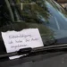 Handgeschriebener Zettel nach einem Parkrempler unter dem Scheibenwischer eines geparkten Autos, mit teilweise verdeckter und nicht lesbarer Telefonnummer