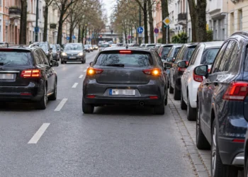 Auto steht mit eingeschaltetem Warnblinker in zweiter Reihe neben parkenden Fahrzeugen