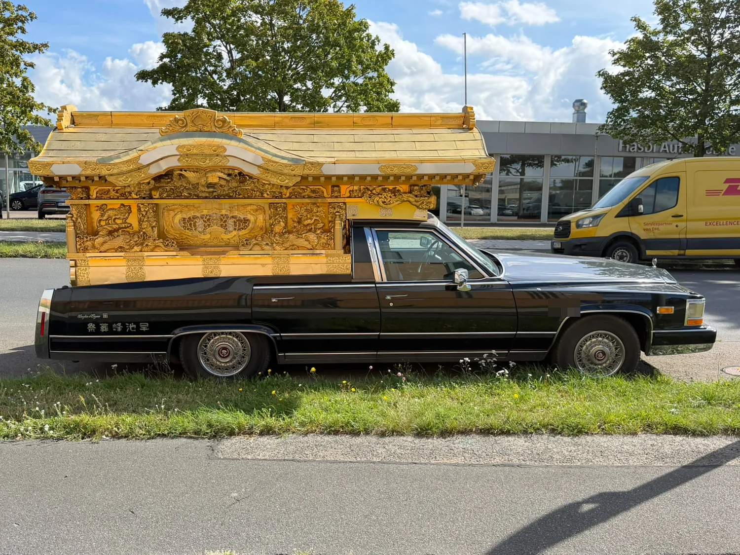 Seitenansicht des schwarzen Cadillac mit vergoldetem Tempelaufbau, der fast die gesamte hintere Fahrzeuglänge einnimmt.