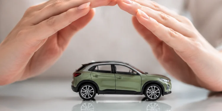 Frauenhände schützen ein kleines grünes Spielzeugauto als Symbolbild für Kfz-Versicherung
