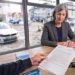 Kundengespräch am Tresen einer Autovermietung, im Hintergrund ein Mietwagen vor dem Schaufenster
