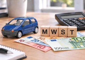 Blaues Modellauto neben Holzwürfeln mit der Aufschrift MWST, Euro-Banknoten und einem Taschenrechner auf einem Schreibtisch