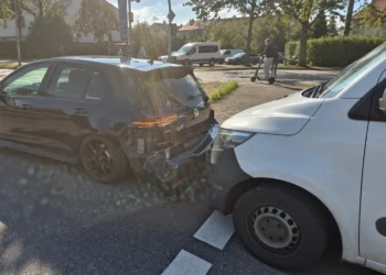 Schwarzer VW Golf mit beschädigtem Heck und weißer Transporter unmittelbar dahinter auf einer Stadtstraße.
