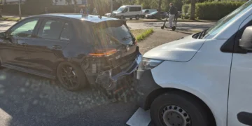 Schwarzer VW Golf mit beschädigtem Heck und weißer Transporter unmittelbar dahinter auf einer Stadtstraße.