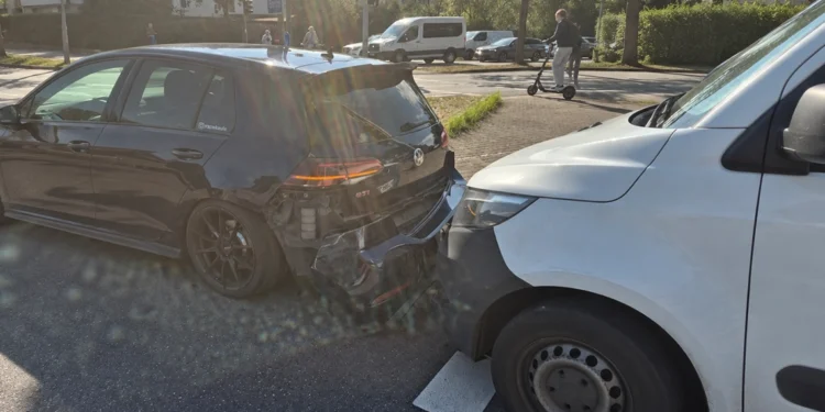 Schwarzer VW Golf mit beschädigtem Heck und weißer Transporter unmittelbar dahinter auf einer Stadtstraße.